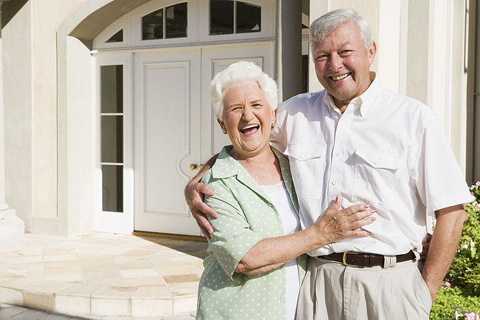 Senior couple standing outside house